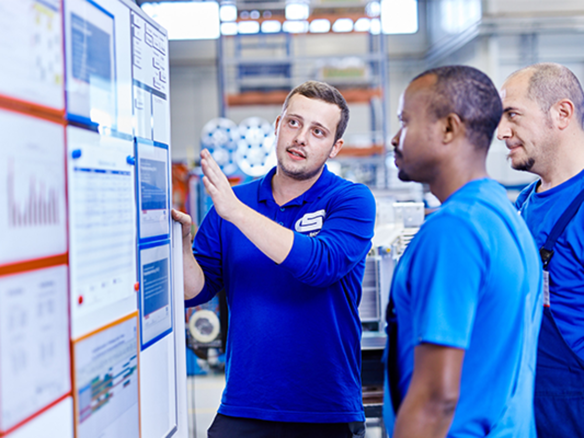 Mitarbeitende stehen zusammen vorm Arbeitsplan