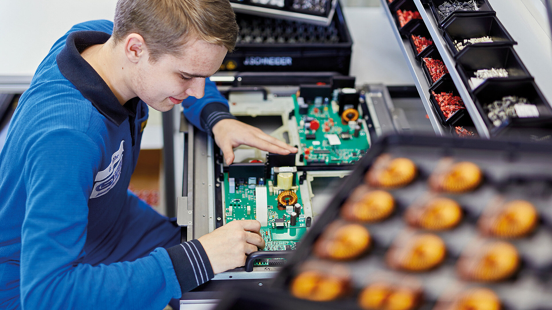 [Translate to English:] Azubi Elektroniker für Geräte und Systeme bestückt Platine