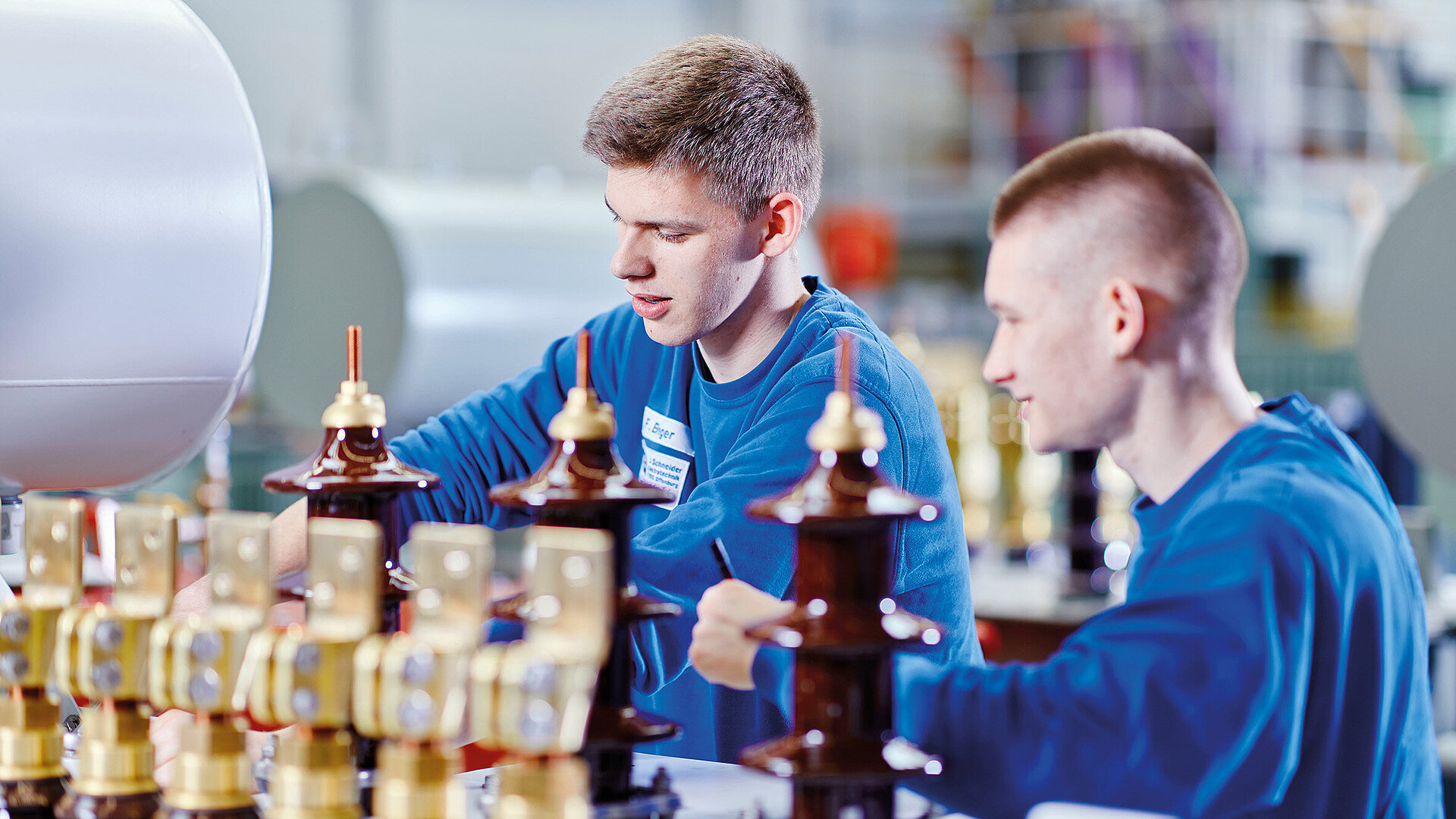 [Translate to English:] zwei Elektroniker für Maschinen- und Antriebstechniker, die an einem Trafo arbeiten