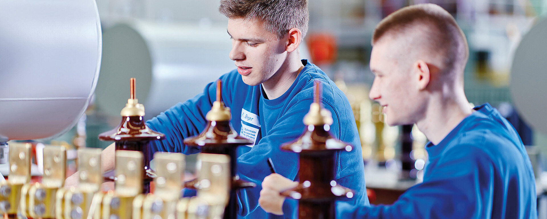 [Translate to English:] zwei Elektroniker für Maschinen- und Antriebstechnik arbeiten an einem Trafo